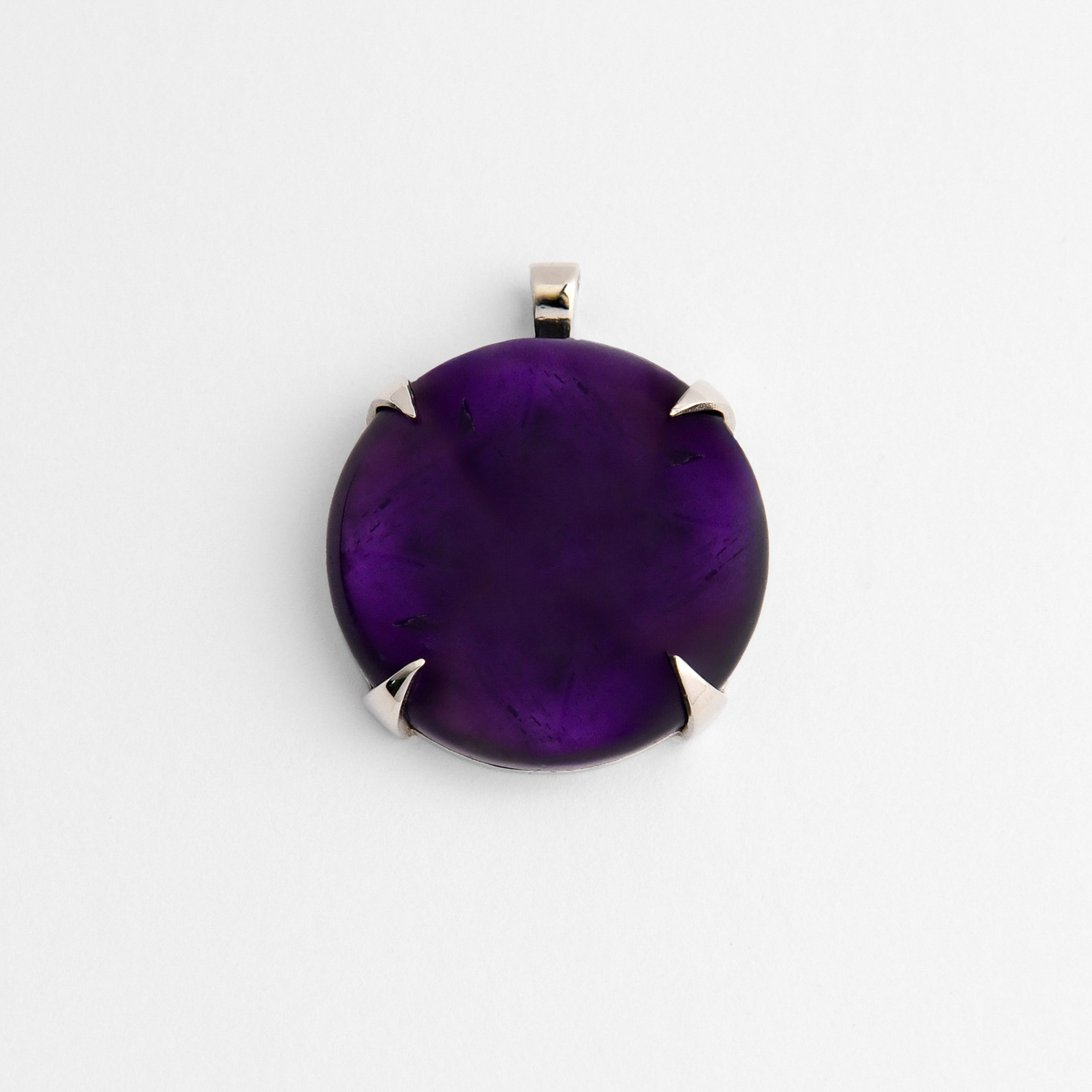 Spar, a round pendant in cool, silvery white bronze, with four triangular claws holding rich purple amethyst, ranging from deep violet to brighter translucent purple. As a natural stone, each piece varies.