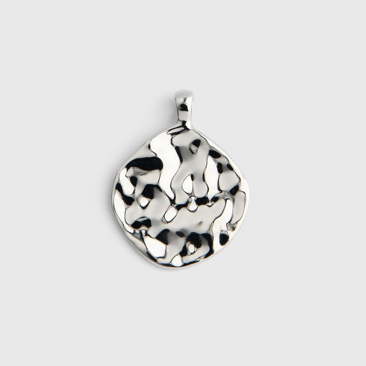 Vea, an irregularly rounded pendant in cool, silvery white bronze, with a hammered surface creating an uneven, dappled pattern of light and shadow.