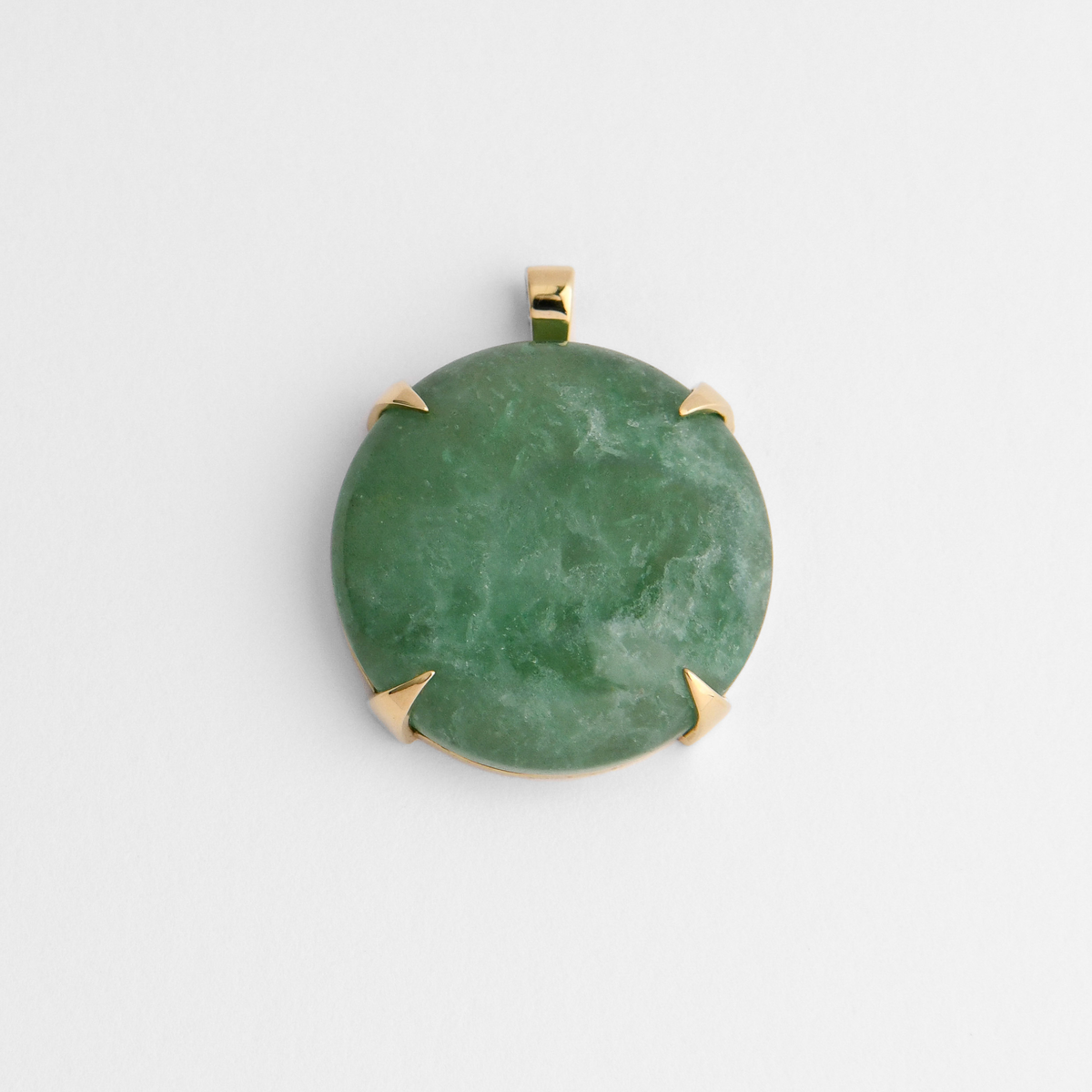 Spar, a round pendant in warm, golden-yellow brass, with four triangular claws holding soft green aventurine, naturally mottled with lighter and deeper shades of green. As a natural stone, each piece varies.