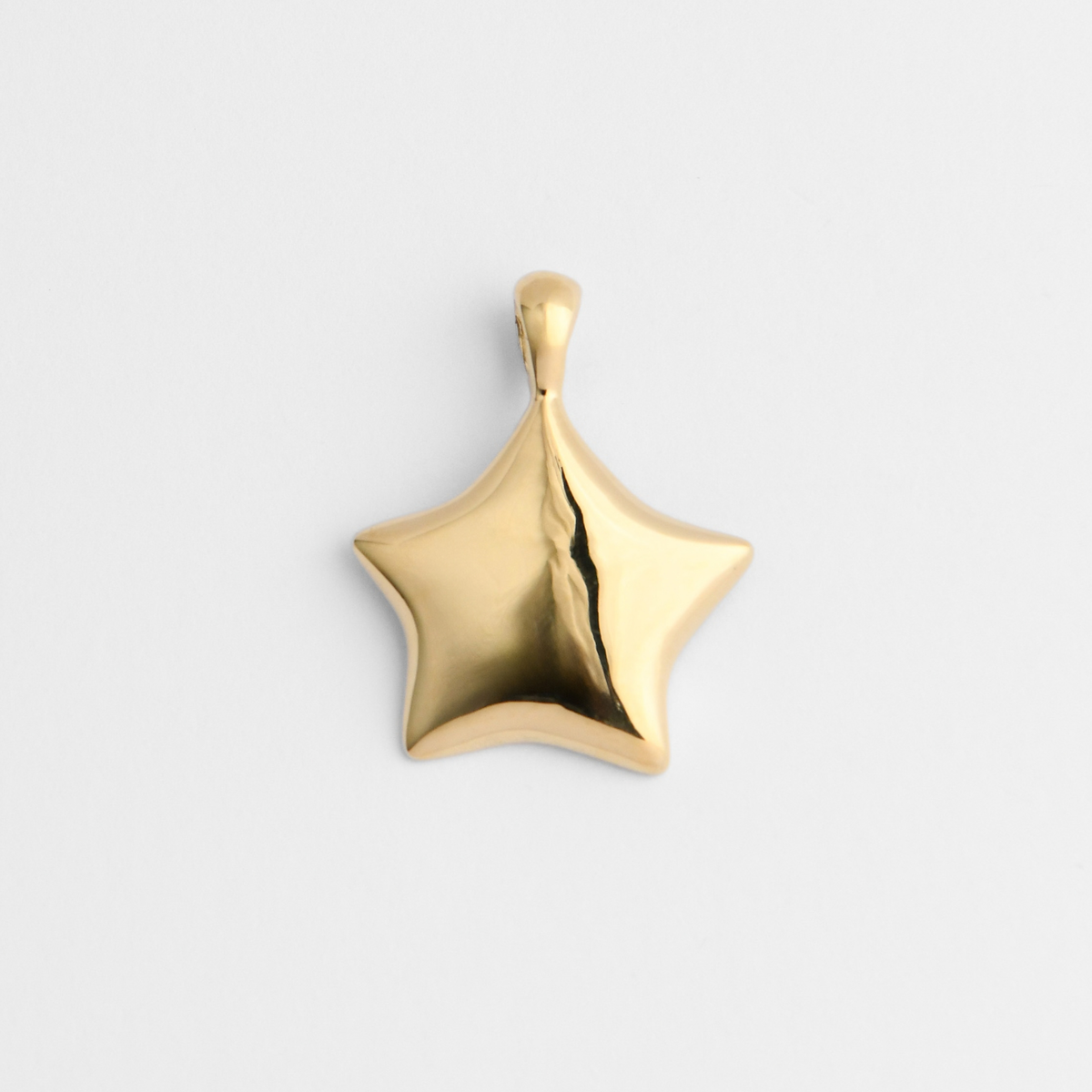 Lyre, a smooth five-pointed star pendant in warm, golden-yellow brass, with softly rounded, slightly curved points and a gently domed surface.