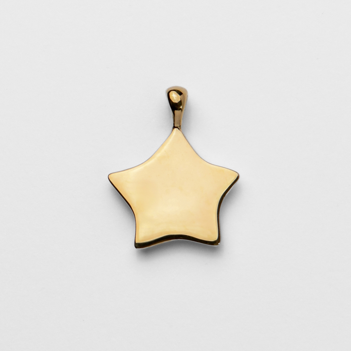 Back of Lyre, a five-pointed star pendant in warm, golden-yellow brass, showing its smooth, flat reverse for personalised engraving.