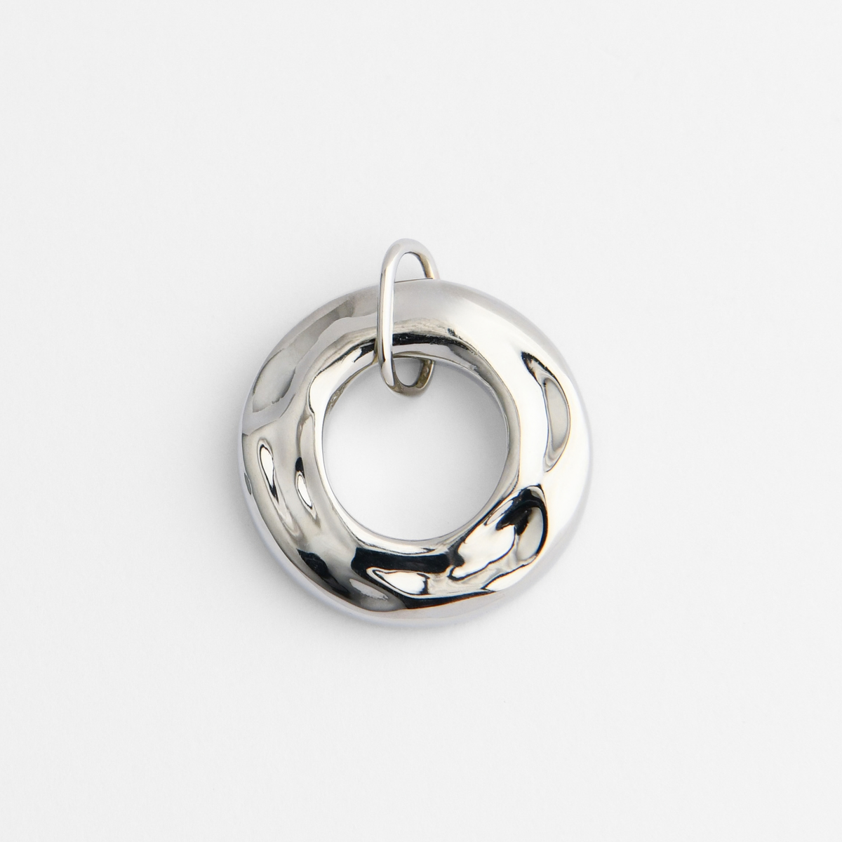 Dromi, a thick, rounded ring pendant in cool, silvery white bronze, with a smooth, softly irregular surface and a large circular opening at its centre.