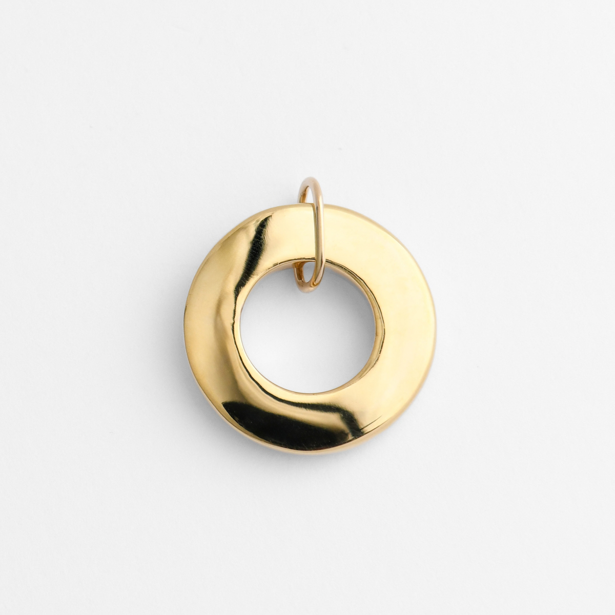 Back of Dromi, a rounded ring pendant in warm, golden-yellow brass, showing its smooth, flat reverse for personalised engraving.