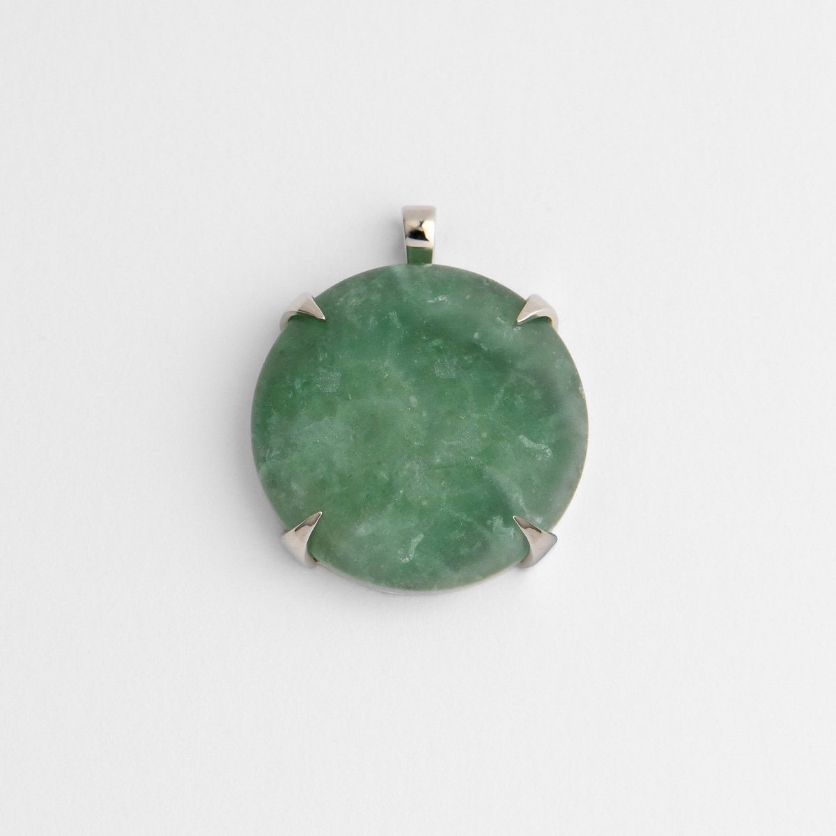 Spar, a round pendant in cool, silvery white bronze, with four triangular claws holding soft green aventurine, naturally mottled with lighter and deeper shades of green. As a natural stone, each piece varies.