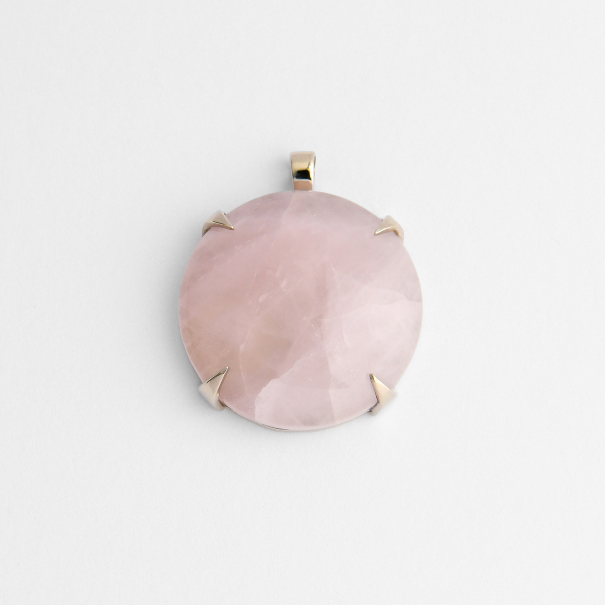 Spar, a round pendant in cool, silvery white bronze, with four triangular claws holding pale pink rose quartz, softly translucent with natural variations in tone. As a natural stone, each piece varies.