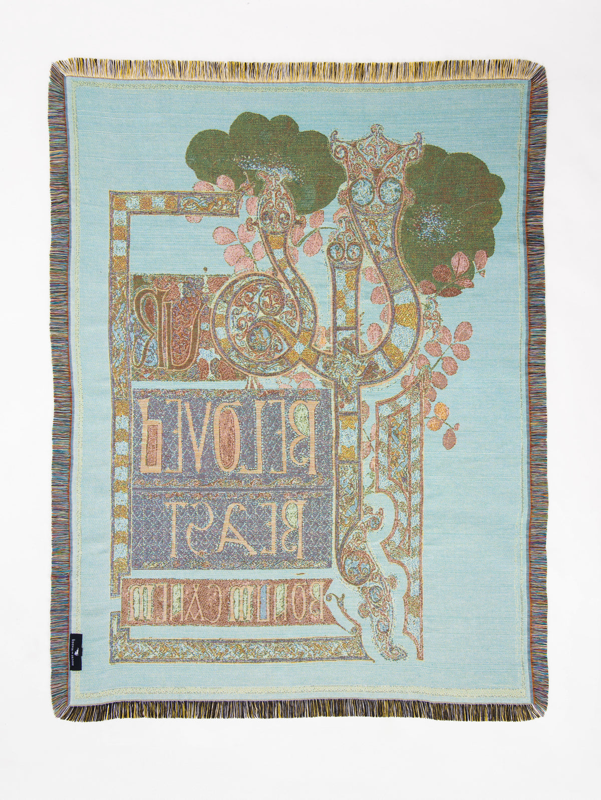 Reverse of the Beloved Beast woven throw in soft powder blue, with the two ornate serpent-like beasts woven in pale blue, gold and muted rust among dusky pink foliage and deep olive flowers. One serpent forms the beginning of the letter Y in the reversed “YOUR BELOVED BEAST” design, with intricate ornamental borders and the Latin motto “PRO AMORE FERARUM” below.