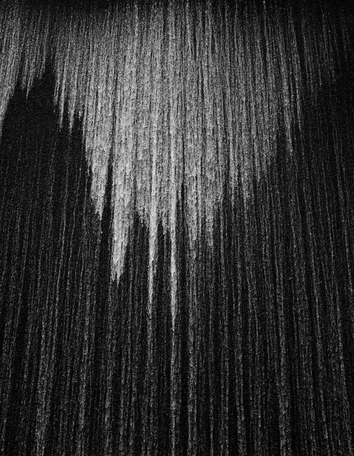 Falling water caught in a black-and-white photograph, cascading in silvery threads through the darkness like a chandelier.
